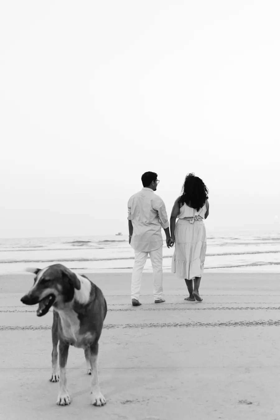 Bride and groom embracing on the beach, her veil drifting in the breeze